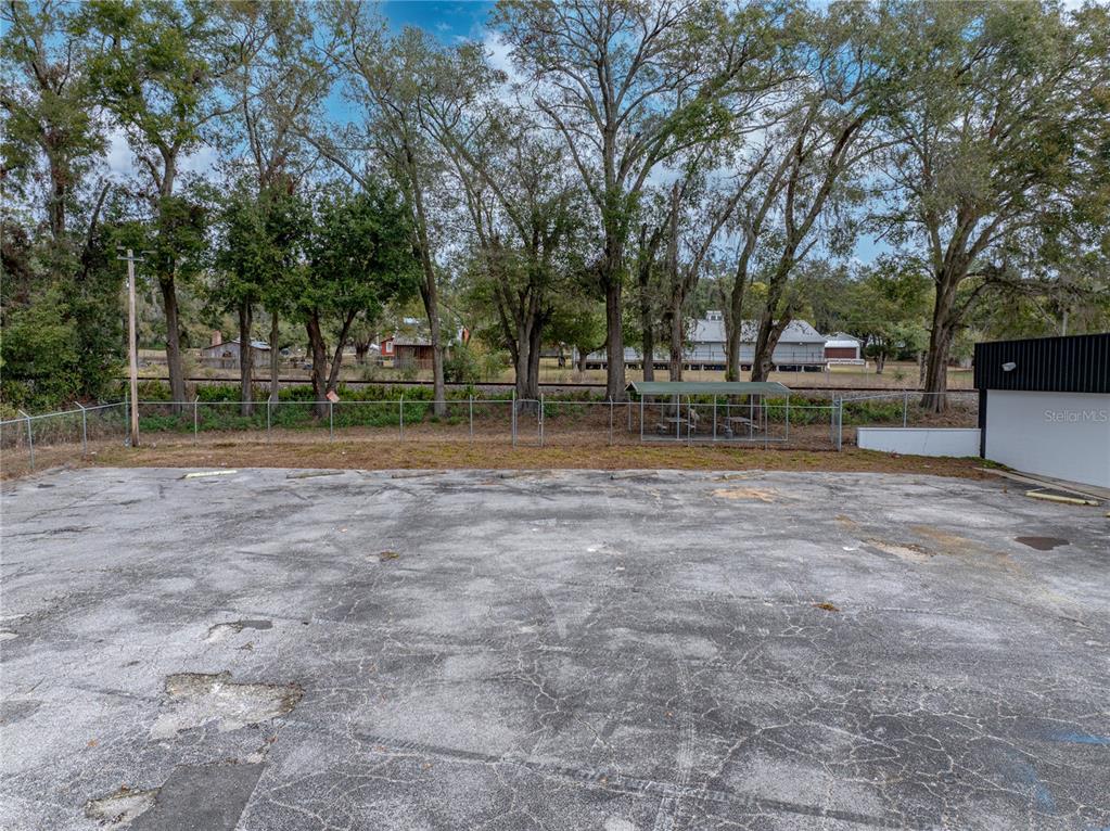 A paved parking lot is enclosed by a chain-link fence with trees in the background — 15552 US HIGHWAY 301, DADE CITY, FL