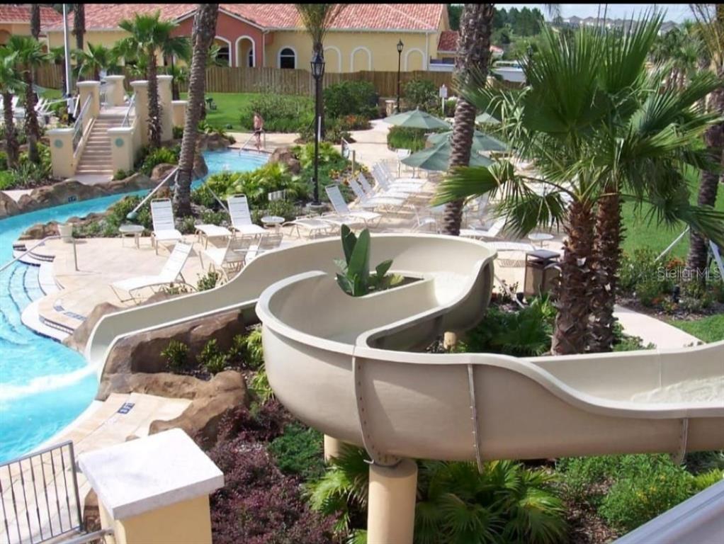 A view of a resort-style swimming pool with a water slide and lounge chairs — 216 CALABRIA AVENUE, DAVENPORT, FL