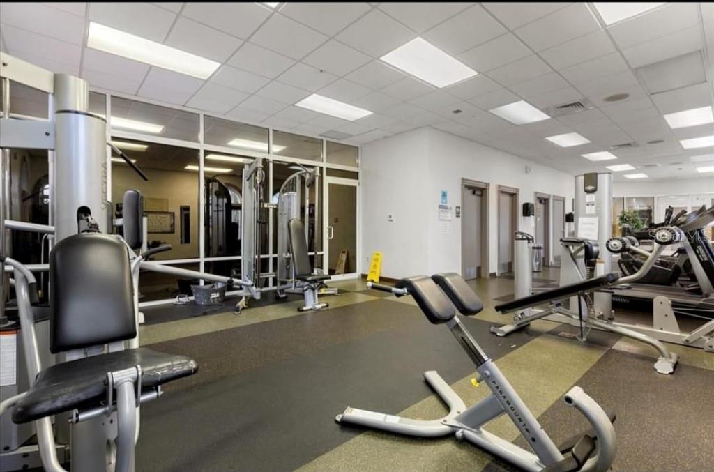 A bright fitness center featuring various exercise machines, rubber flooring, and large windows — 216 CALABRIA AVENUE, DAVENPORT, FL