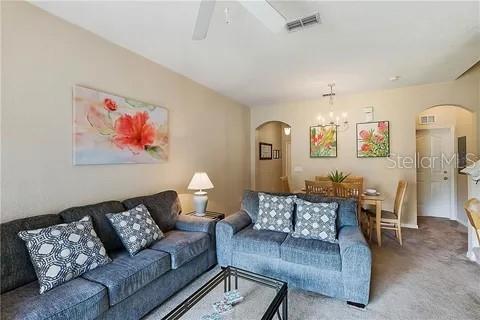 A living room with two gray sofas, a glass coffee table, and a dining area — 216 CALABRIA AVENUE, DAVENPORT, FL