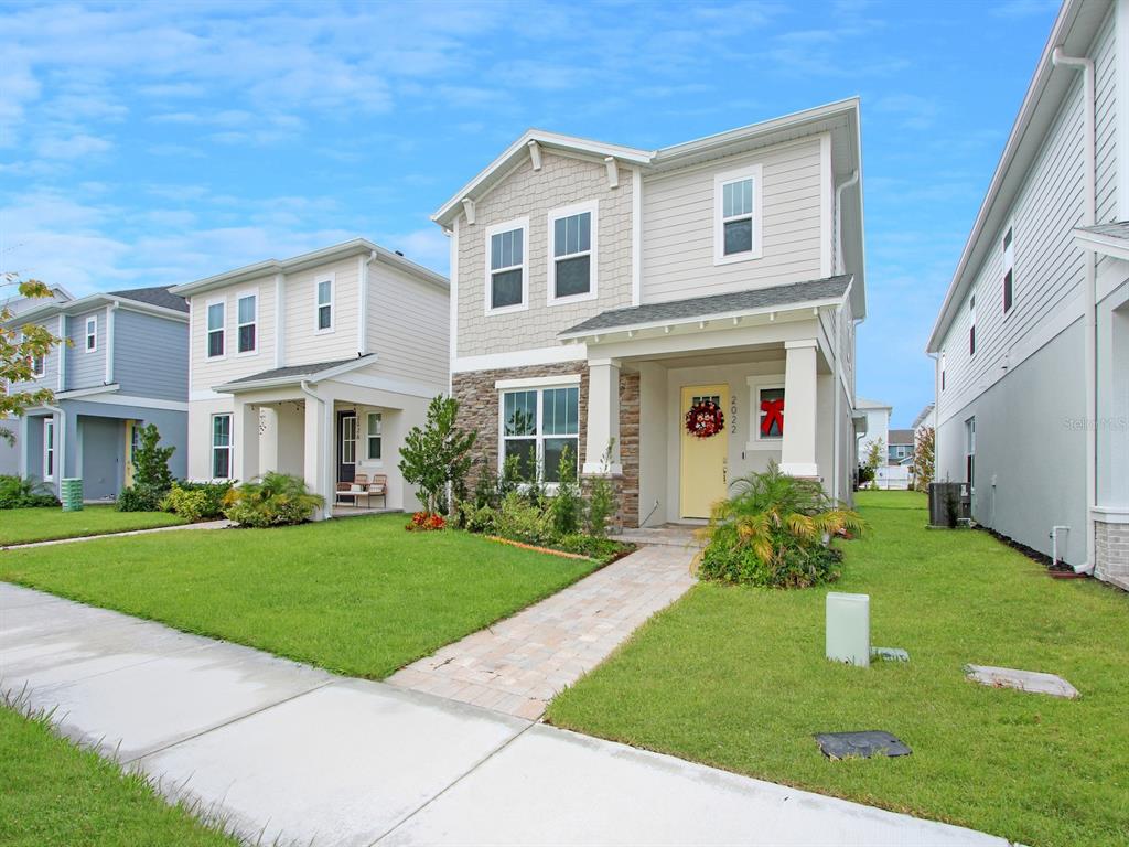 A two-story suburban house with a yellow front door and a stone-accented facade — 2022 EDUCATION STREET, ST CLOUD, FL