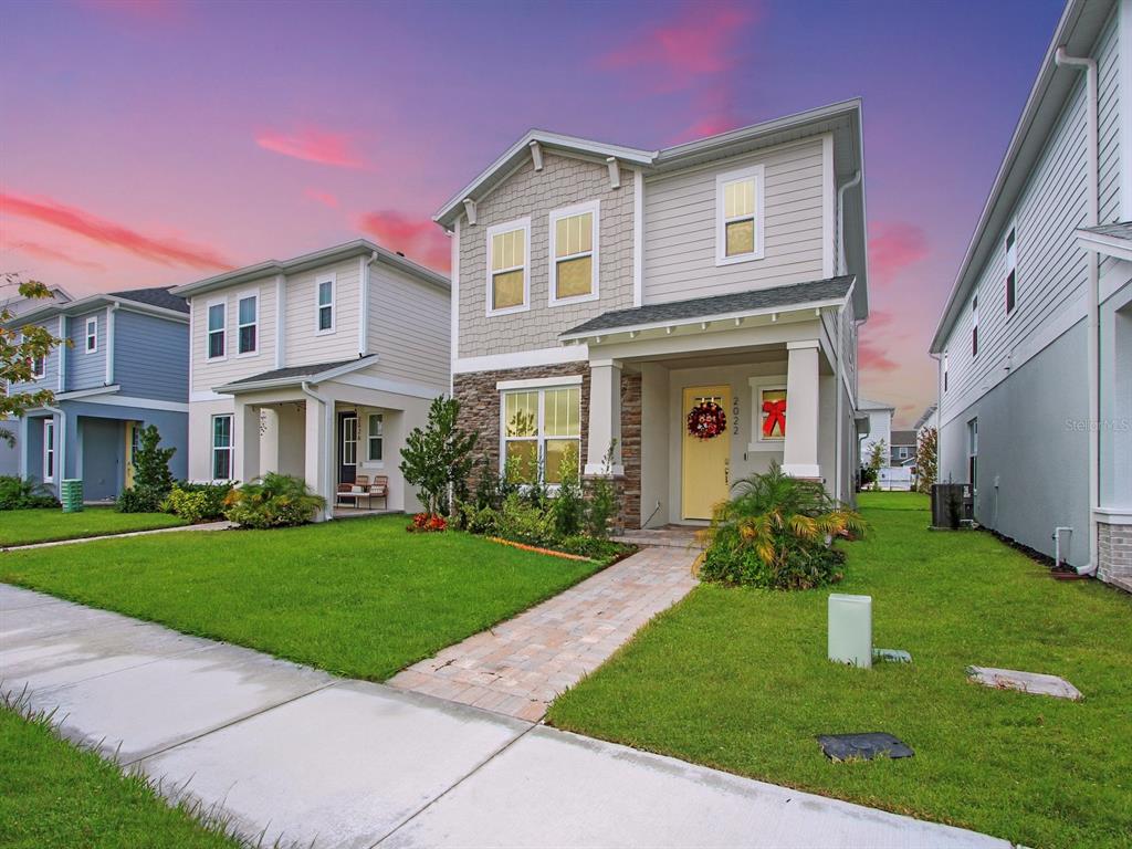 A two-story suburban house with a yellow front door and a stone-accented facade — 2022 EDUCATION STREET, ST CLOUD, FL