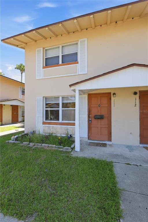 A two-story tan apartment building with a concrete walkway and a small front garden — 1600 S PALMETTO AVENUE UNIT 111, SOUTH DAYTONA, FL
