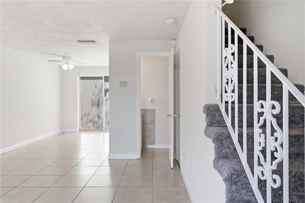 A room with tile flooring, a staircase with gray carpet, and an open doorway — 1600 S PALMETTO AVENUE UNIT 111, SOUTH DAYTONA, FL