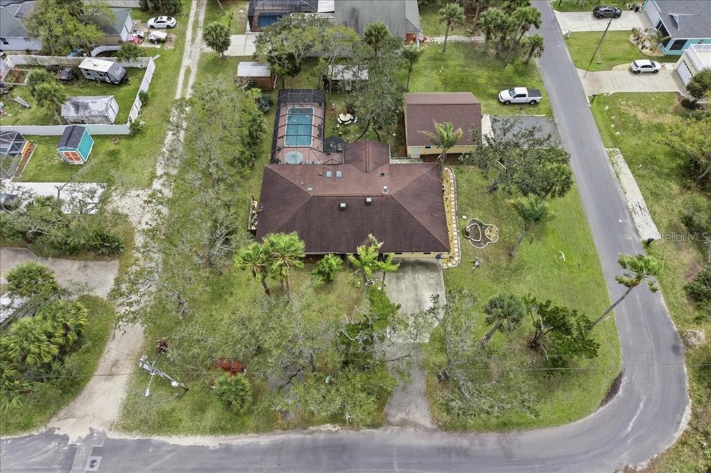 An aerial view shows a house with a brown roof, a pool, and a detached garage — 411 S 19TH STREET, FLAGLER BEACH, FL
