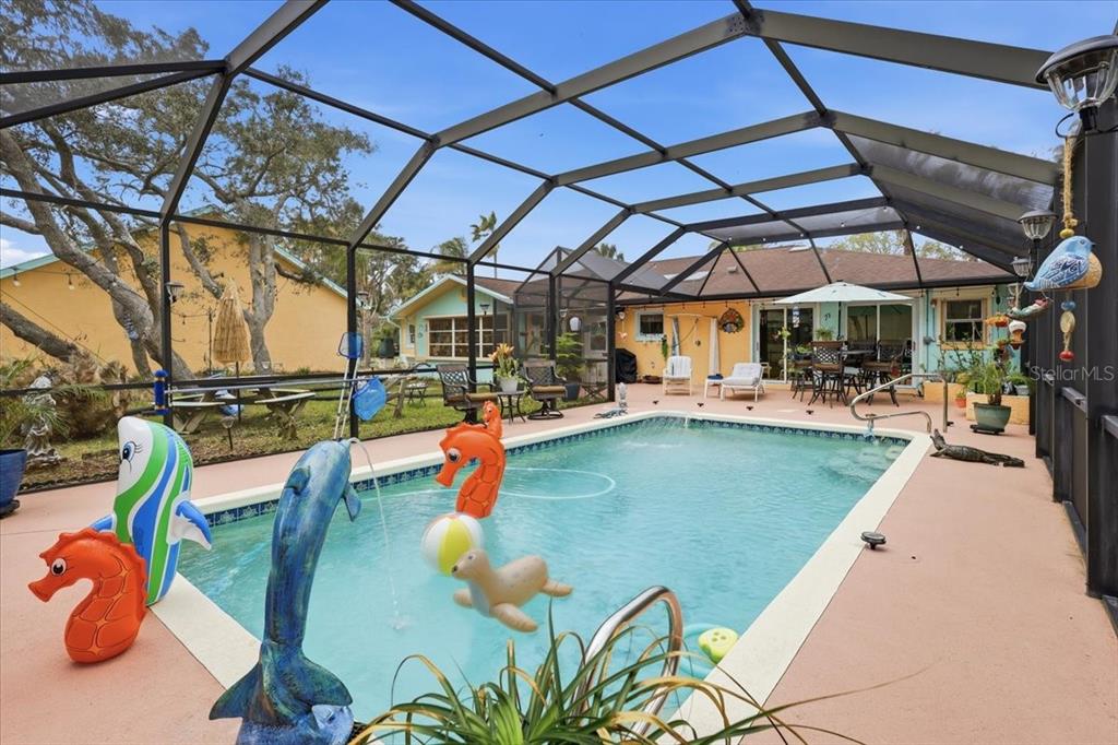 A screened-in swimming pool area features a patio with outdoor furniture and inflatable toys — 411 S 19TH STREET, FLAGLER BEACH, FL