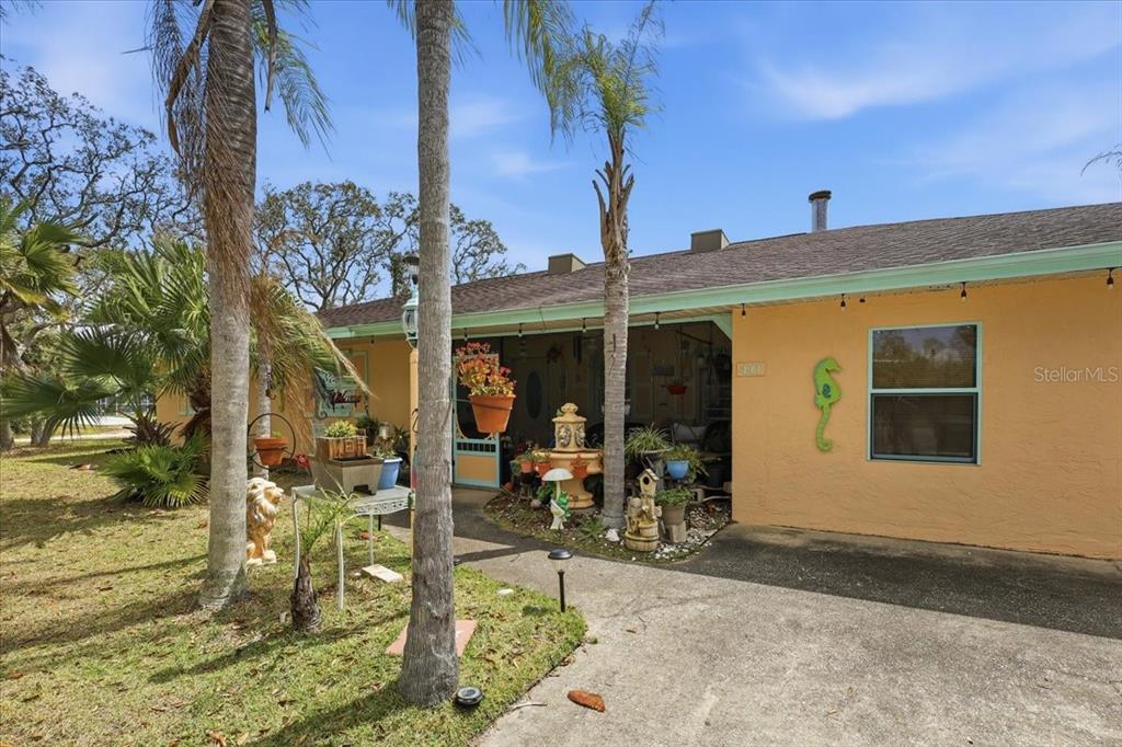 A single-story house with a yellow stucco exterior, a covered entryway, and a concrete driveway — 411 S 19TH STREET, FLAGLER BEACH, FL