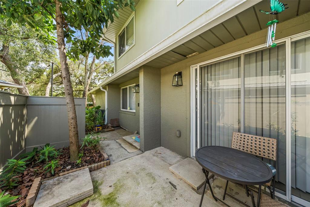 A concrete patio features a small table, a sliding glass door, and a privacy fence — 4586 PHEASANT RUN DRIVE UNIT 6B, ORLANDO, FL