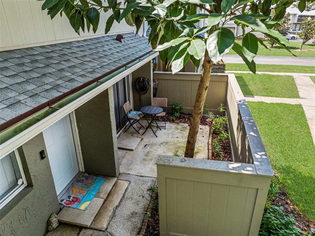An elevated view of a small concrete patio with a table, chairs, and a tree — 4586 PHEASANT RUN DRIVE UNIT 6B, ORLANDO, FL