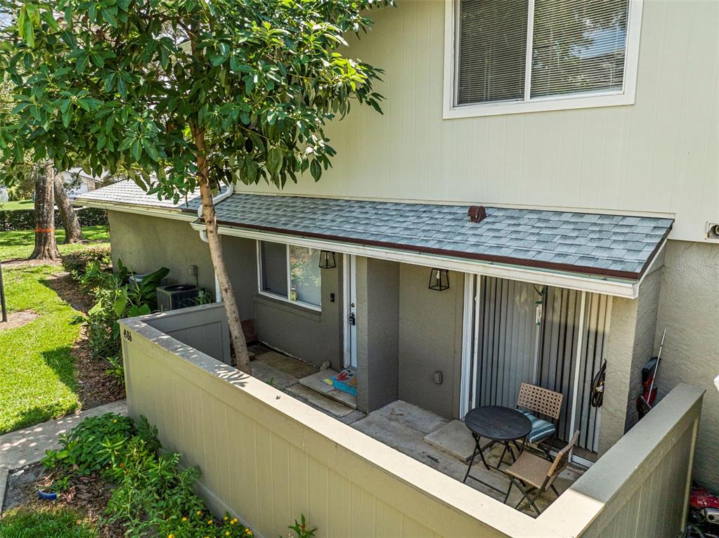 A small patio with a table and chairs sits behind a low wall by a house — 4586 PHEASANT RUN DRIVE UNIT 6B, ORLANDO, FL