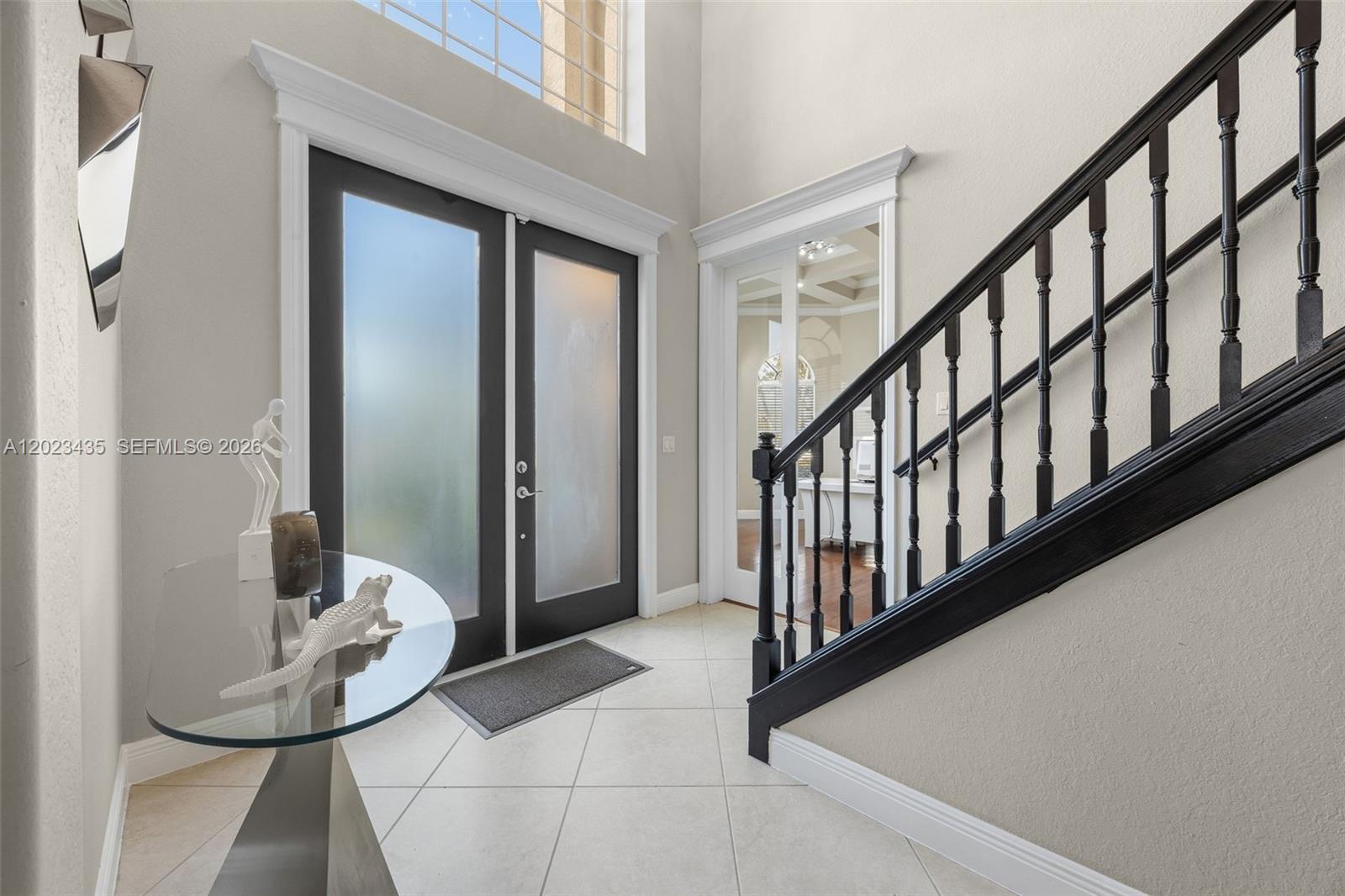 A bright entryway features a glass console table, a black staircase, and frosted double doors — 14832 INDIGO LAKES CIR, Naples FL 34119, NAPLES, FL