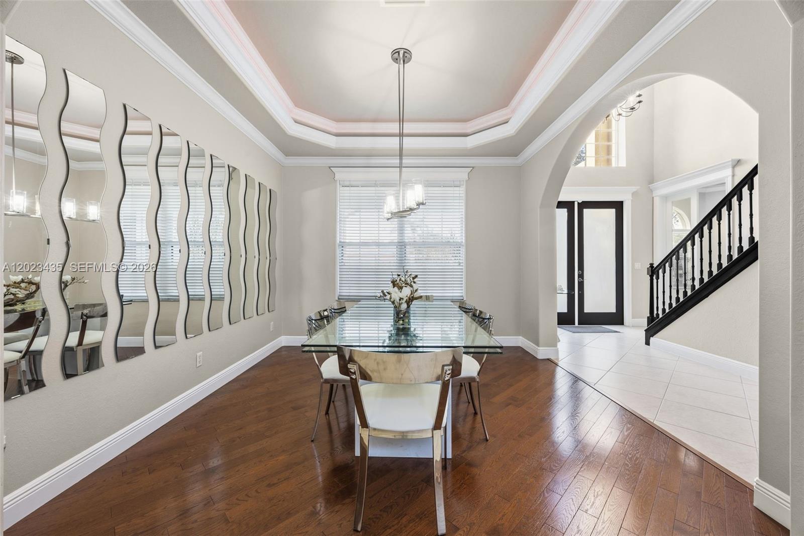 A dining room features a glass table, wavy wall mirrors, and a tray ceiling — 14832 INDIGO LAKES CIR, Naples FL 34119, NAPLES, FL