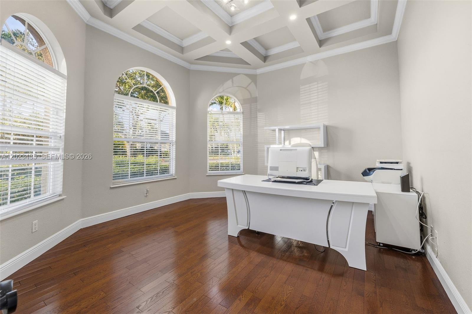 A home office features a white desk, hardwood floors, and arched windows under a tray ceiling — 14832 INDIGO LAKES CIR, Naples FL 34119, NAPLES, FL