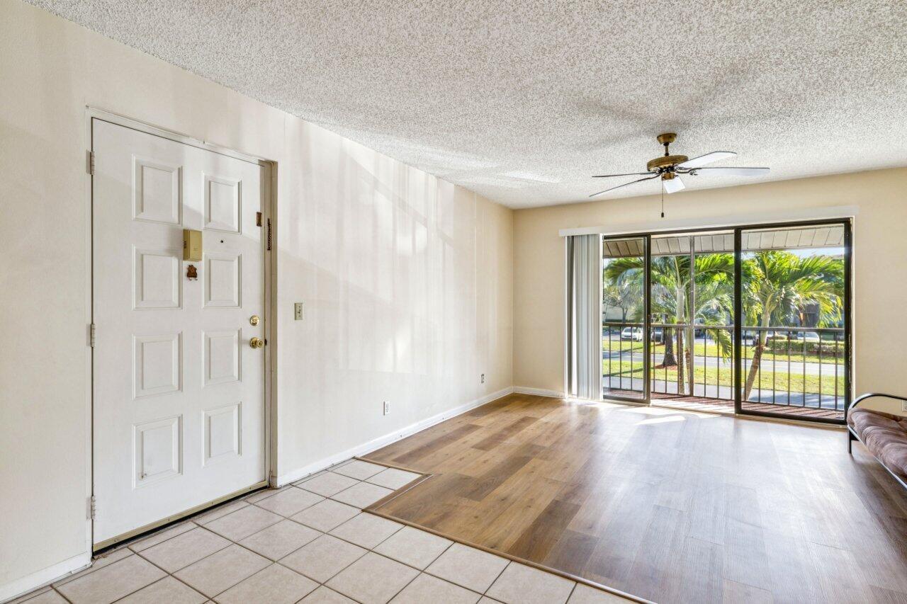 A living room with tile flooring near the entrance, wood-look flooring, and a sliding glass door — 618 Sea Pine Way # A2, FL 33415, FL