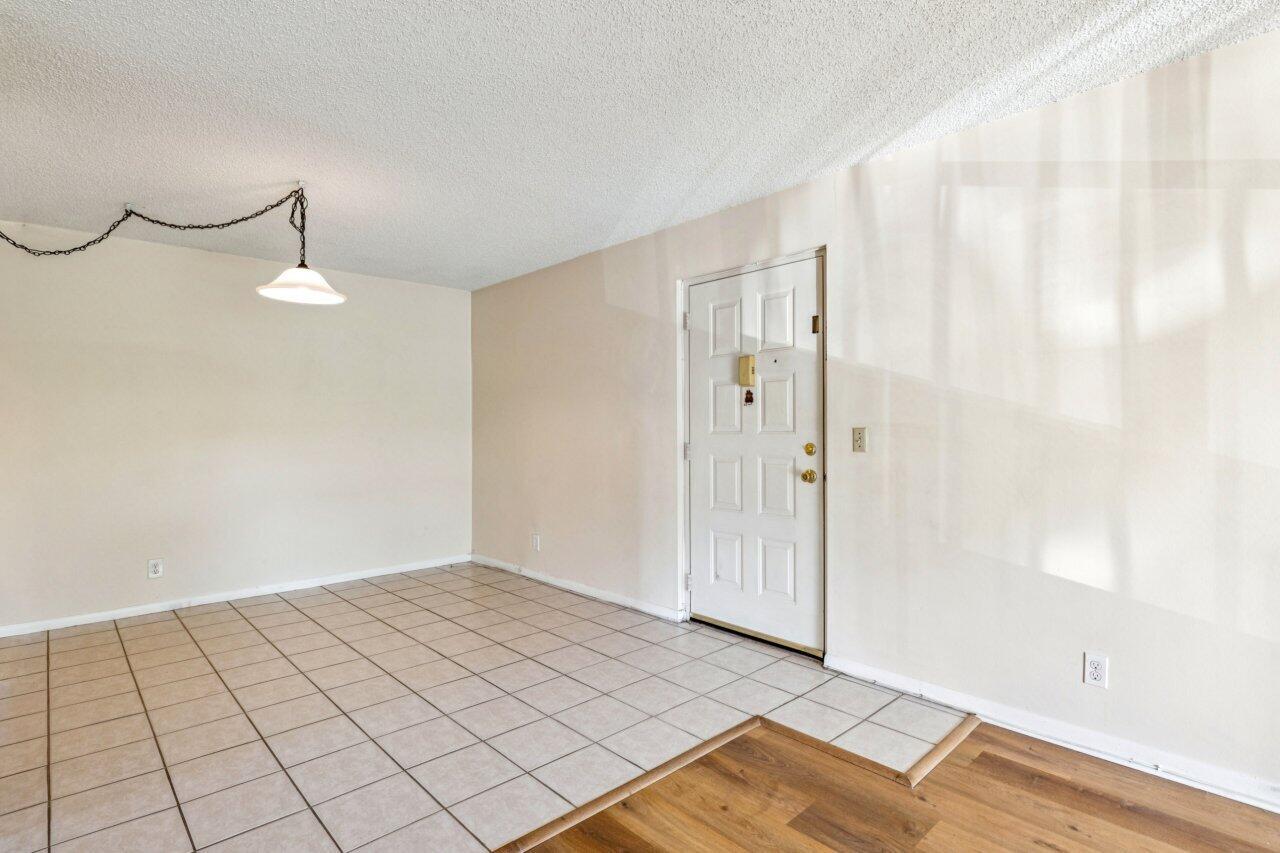 A room with beige walls, a tiled floor, a pendant light, and a white door — 618 Sea Pine Way # A2, FL 33415, FL