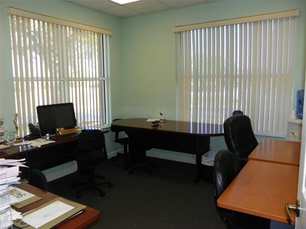 An office room features multiple desks, black chairs, and large windows with vertical blinds — 2824 MANATEE AVENUE E, BRADENTON, FL