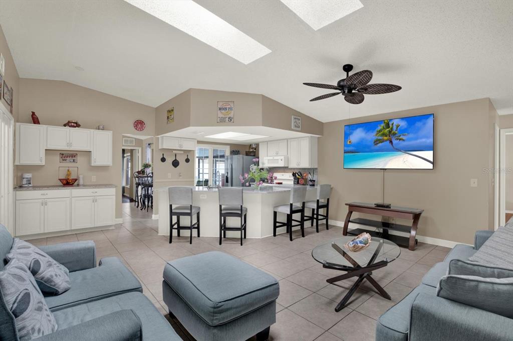 A living room with tile flooring, a kitchen island with bar stools, and a television — 729 SANDY CREEK DRIVE, BRANDON, FL
