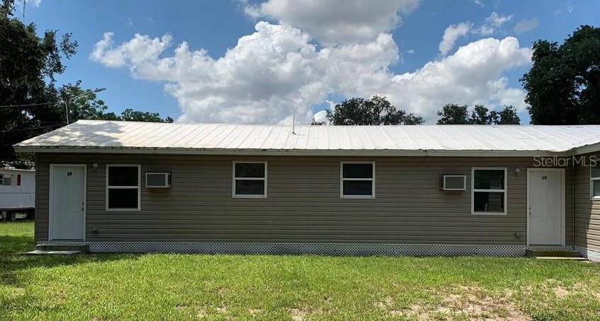 A single-story building with tan siding, a white metal roof, and two white entry doors — 110 FOREST AVENUE UNIT 11, DAVENPORT, FL