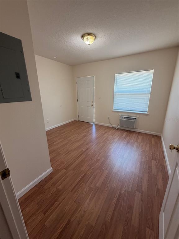 An empty room with wood-look flooring, a window with blinds, and a wall-mounted air conditioner — 110 FOREST AVENUE UNIT 11, DAVENPORT, FL