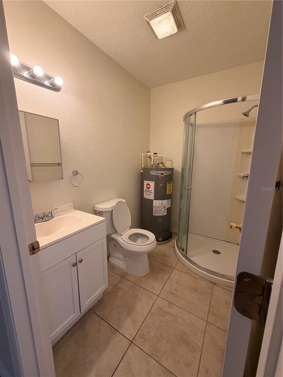A bathroom features a white vanity, a toilet, a corner shower, and a water heater — 110 FOREST AVENUE UNIT 11, DAVENPORT, FL
