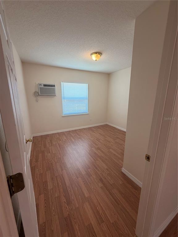 An empty bedroom features wood-look laminate flooring, a window with blinds, and a wall-mounted air conditioner — 110 FOREST AVENUE UNIT 11, DAVENPORT, FL