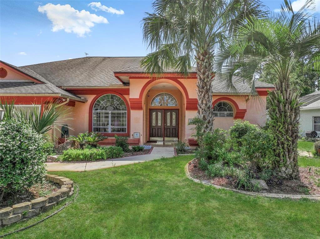 A single-story house with a peach stucco exterior, arched windows, and a central double-door entrance — 22 FORDS WAY, PALM COAST, FL