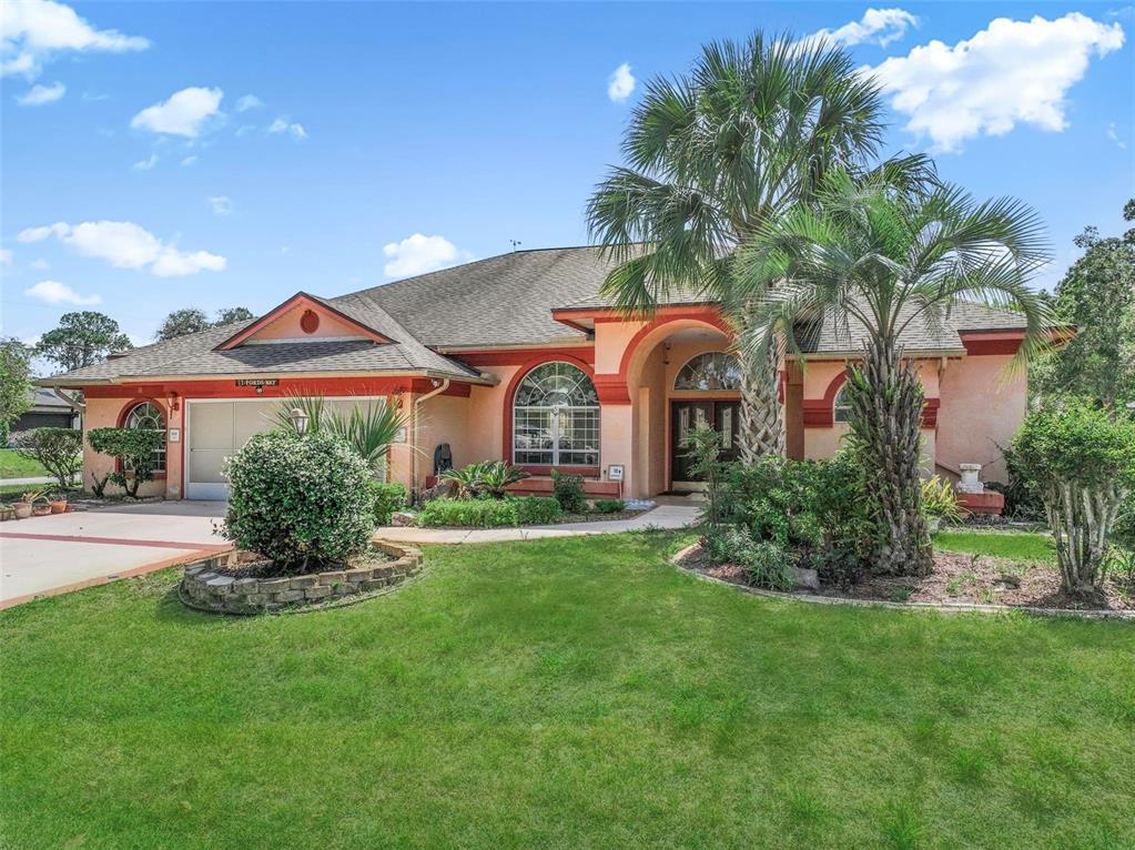 A single-story house with a stucco exterior, a two-car garage, and a palm tree — 22 FORDS WAY, PALM COAST, FL
