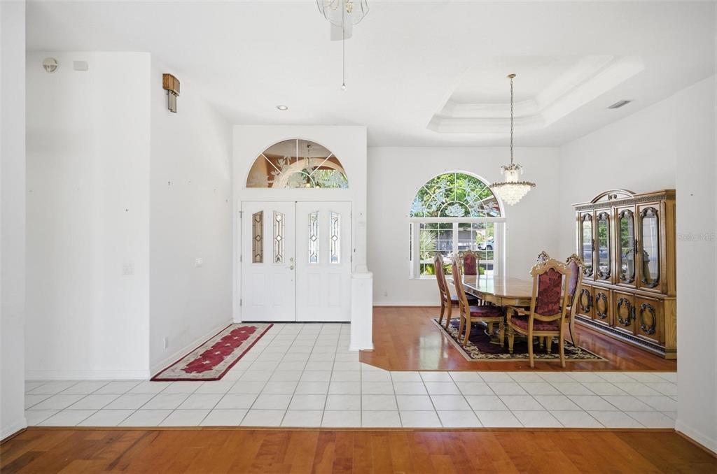 A foyer with tile flooring leads into a dining room featuring hardwood floors and a chandelier — 22 FORDS WAY, PALM COAST, FL