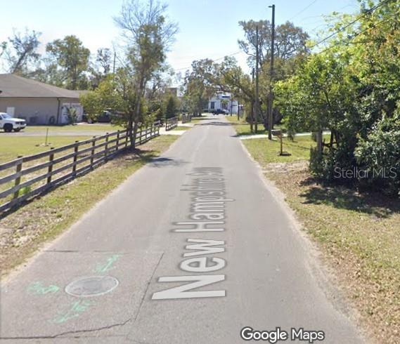 A narrow paved road stretches forward between a wooden fence and trees — 210 N NEW HAMPSHIRE AVENUE, APOPKA, FL