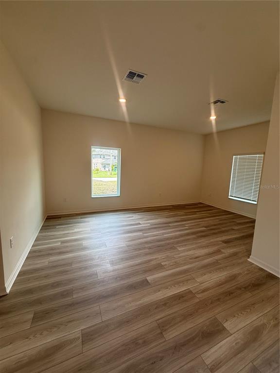 An empty room features light-colored wood-look flooring, beige walls, and two windows — 2921 GARRET STREET, DELTONA, FL