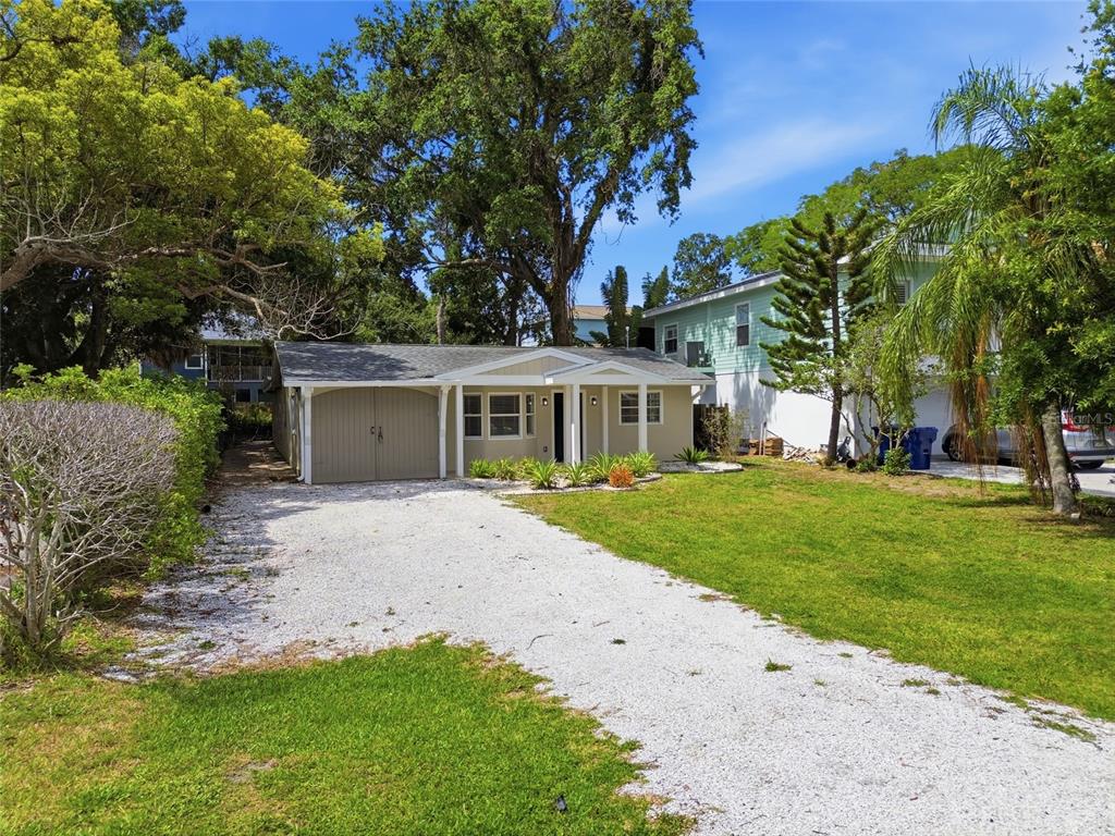 A single-story house with a gravel driveway, attached garage, and surrounding trees — 125 CRYSTAL BEACH AVENUE, CRYSTAL BEACH, FL