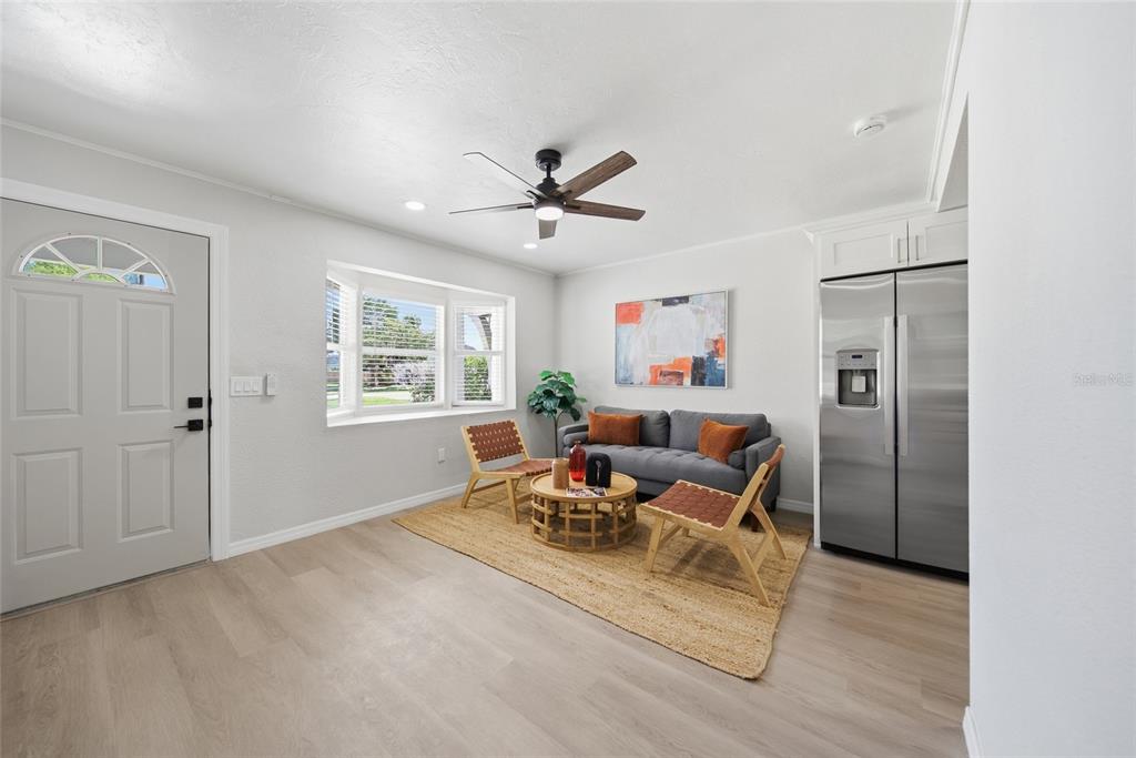 A living area features light wood flooring, a grey sofa, two wooden chairs, and a refrigerator — 125 CRYSTAL BEACH AVENUE, CRYSTAL BEACH, FL