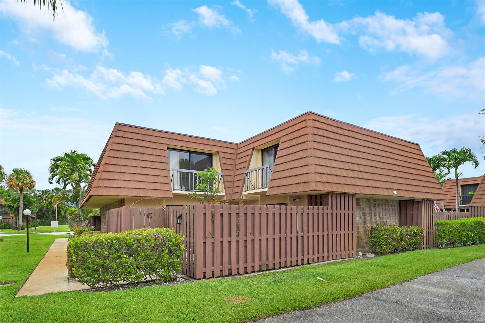 A two-story townhouse with a brown mansard roof and a wooden privacy fence — 825 Center Street # 49c, Jupiter FL 33458, JUPITER, FL