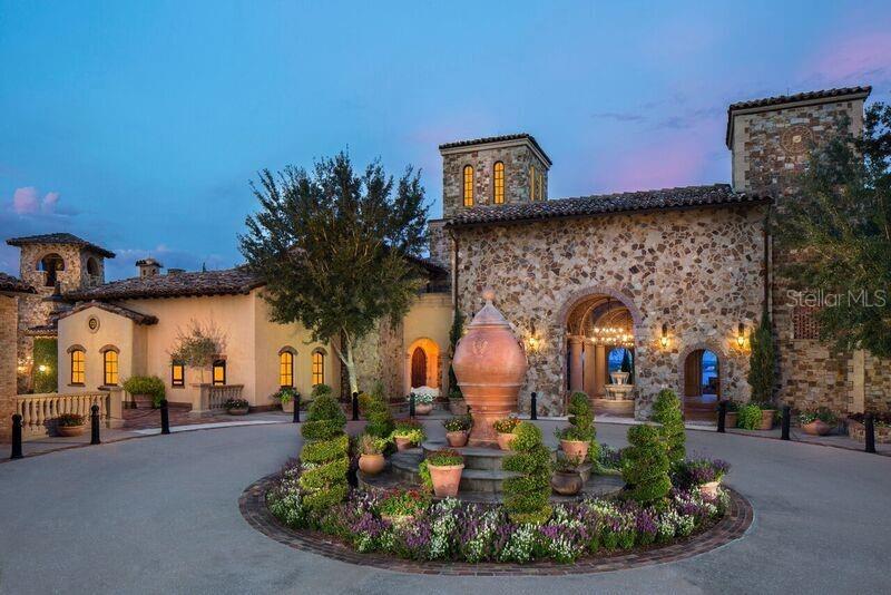 A stone mansion with a circular driveway and a central fountain featuring a large urn — 16122 TRIVOLI CIRCLE, BELLA COLLINA, FL