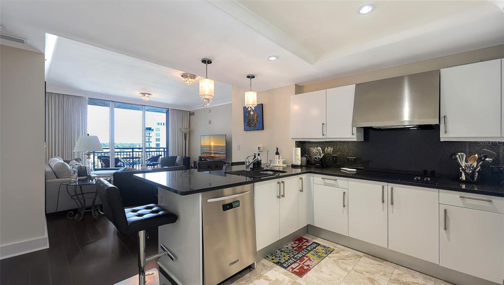 A modern kitchen with white cabinets and black countertops overlooks an open-concept living area — 1350 MAIN STREET UNIT 1007, SARASOTA, FL