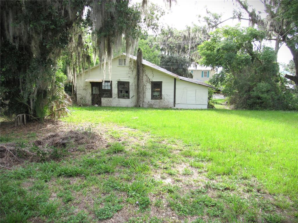 A weathered, light-colored house with a metal roof sits on a large, grassy lot — 14 S LAKE STREET, CRESCENT CITY, FL