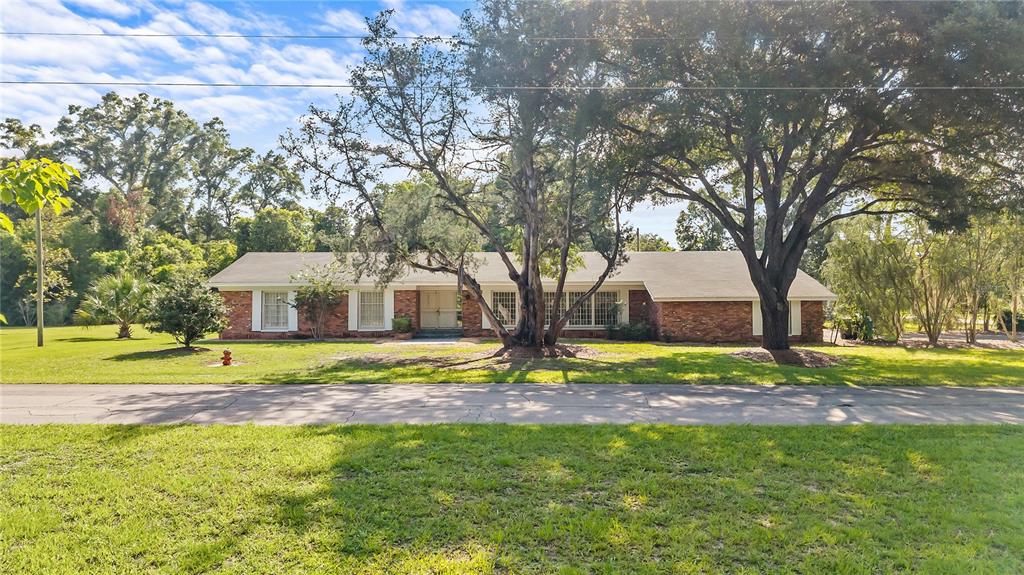 A single-story brick house with a large tree in the front yard — 214 SE 2ND STREET, CHIEFLAND, FL