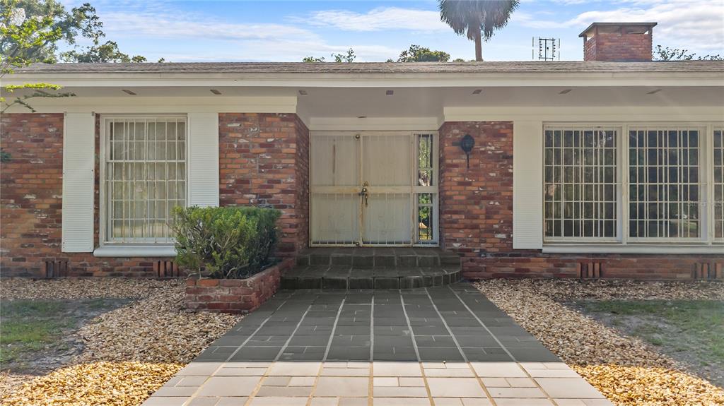 The exterior of a single-story brick house features a paved walkway leading to the front entrance — 214 SE 2ND STREET, CHIEFLAND, FL