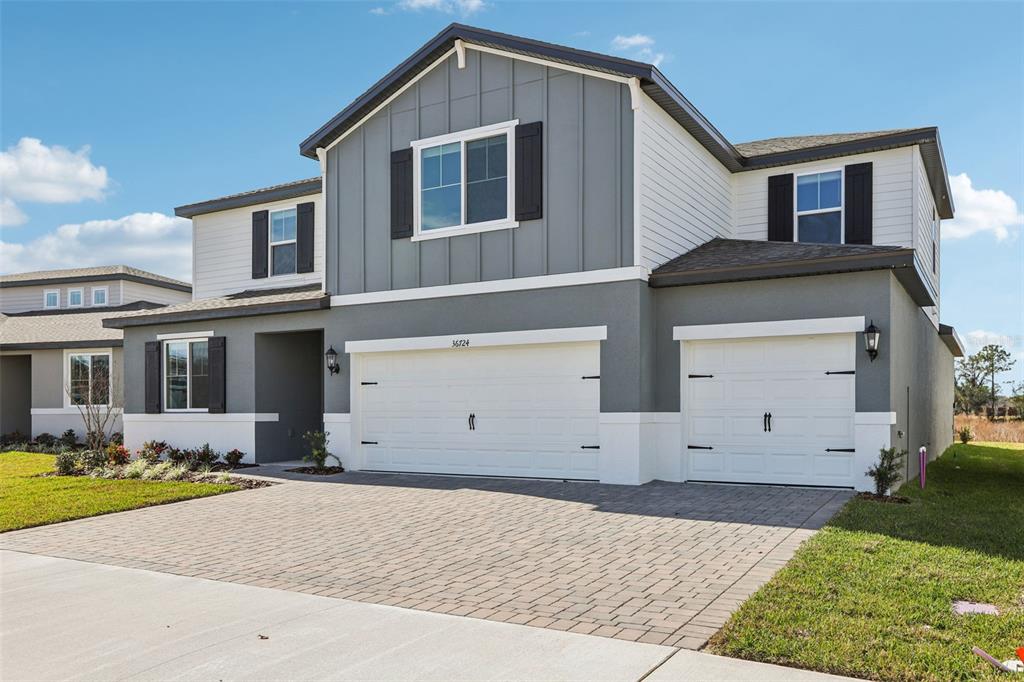 A two-story house with a gray and white exterior and a three-car garage — 36724 MELSTONE WAY, ZEPHYRHILLS, FL