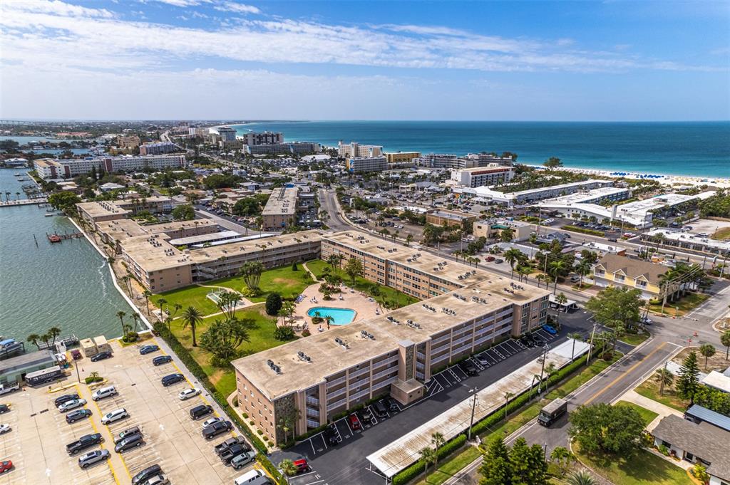An aerial view shows a multi-story apartment complex with a pool and parking lot — 6363 GULF WINDS DRIVE UNIT 437, ST PETE BEACH, FL