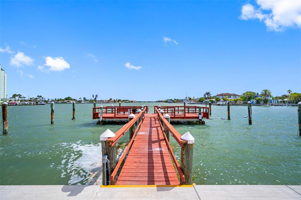 A wooden pier with a T-shaped deck extends over the water under a blue sky — 6363 GULF WINDS DRIVE UNIT 437, ST PETE BEACH, FL