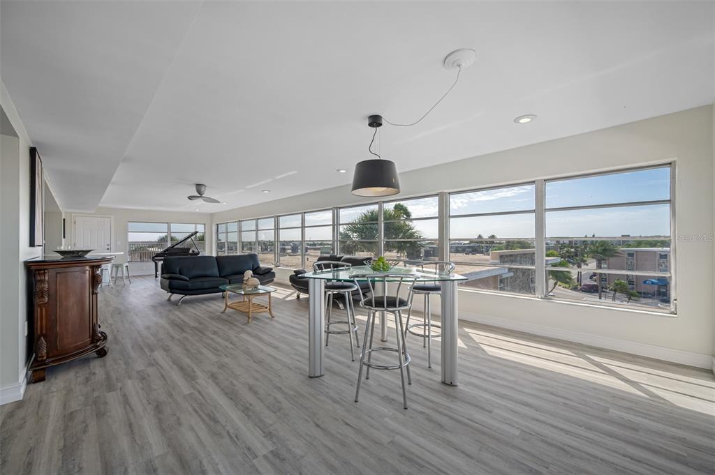 A bright living and dining area features wood-look flooring, a black pendant light, and windows — 6363 GULF WINDS DRIVE UNIT 437, ST PETE BEACH, FL