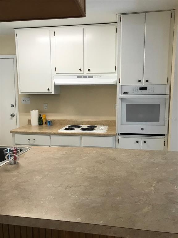 A kitchen features white cabinets, a wall oven, a stovetop, and a large countertop — 3706 NW 7TH AVENUE, GAINESVILLE, FL