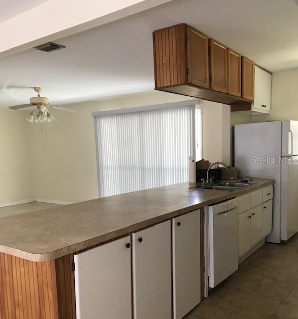 A kitchen features wood-paneled cabinets, a white dishwasher, a white refrigerator, and a breakfast bar — 3706 NW 7TH AVENUE, GAINESVILLE, FL