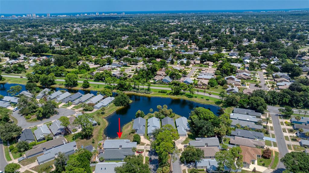 An aerial view shows a residential neighborhood with a lake and a red arrow pointing down — 982 BREEZEMONT COURT, PORT ORANGE, FL