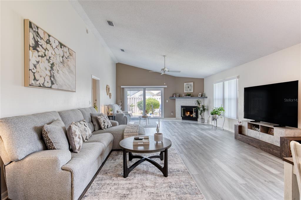 A spacious living room features a grey sectional sofa, a fireplace, and light wood flooring — 982 BREEZEMONT COURT, PORT ORANGE, FL