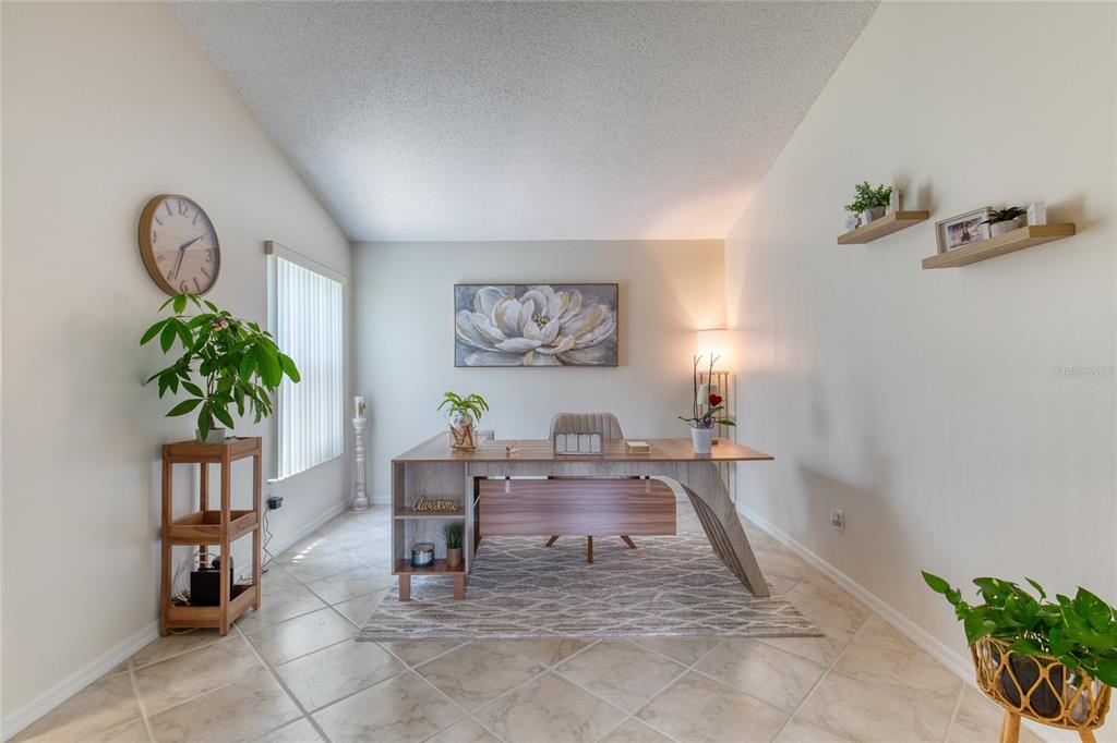 A home office features a modern wood desk, tiled floors, and wall-mounted shelves — 982 BREEZEMONT COURT, PORT ORANGE, FL