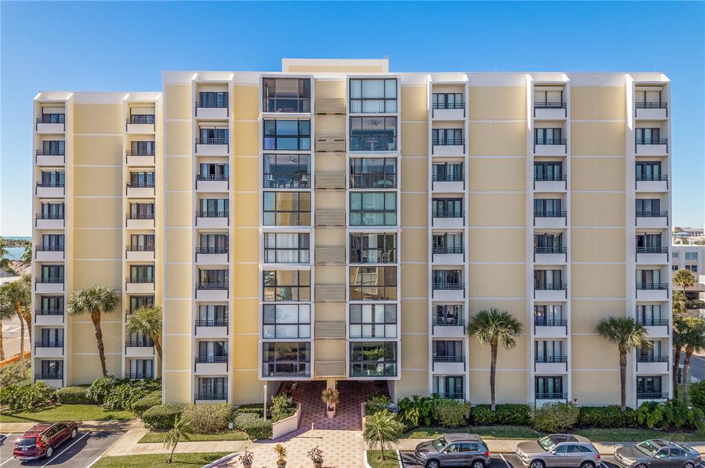 A multi-story, yellow apartment building with balconies and palm trees in front — 800 S GULFVIEW BOULEVARD UNIT 403, CLEARWATER BEACH, FL