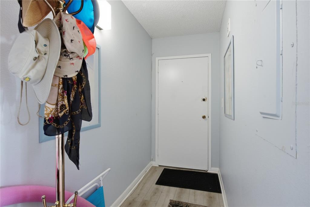 An entryway features light blue walls, wood-look flooring, a white door, and a hat rack — 800 S GULFVIEW BOULEVARD UNIT 403, CLEARWATER BEACH, FL