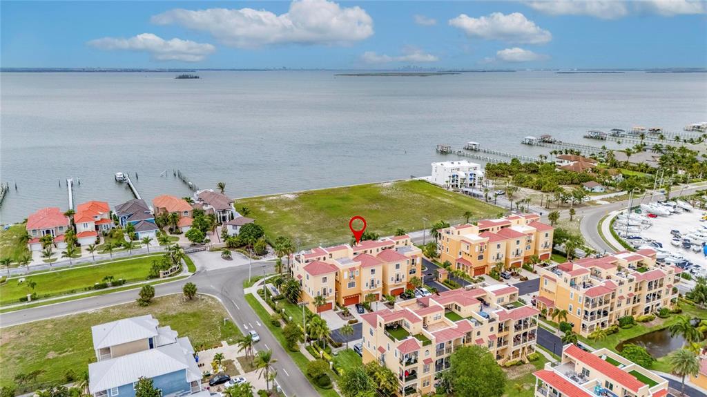 Aerial view of a waterfront residential complex with townhomes and a nearby marina — 6408 MAYRA SHORES LANE, APOLLO BEACH, FL